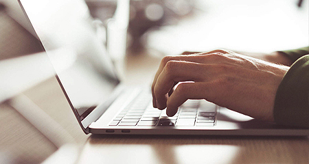 Hands typing on a laptop.