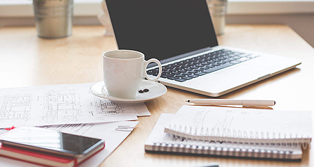 Laptop, cup of tea and notebooks.